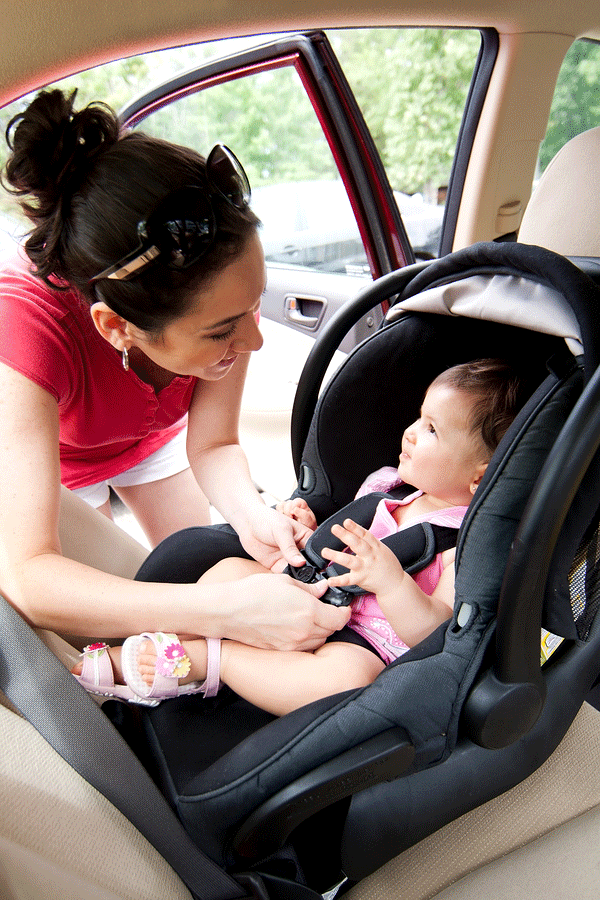 Mother putting child in car seat safely